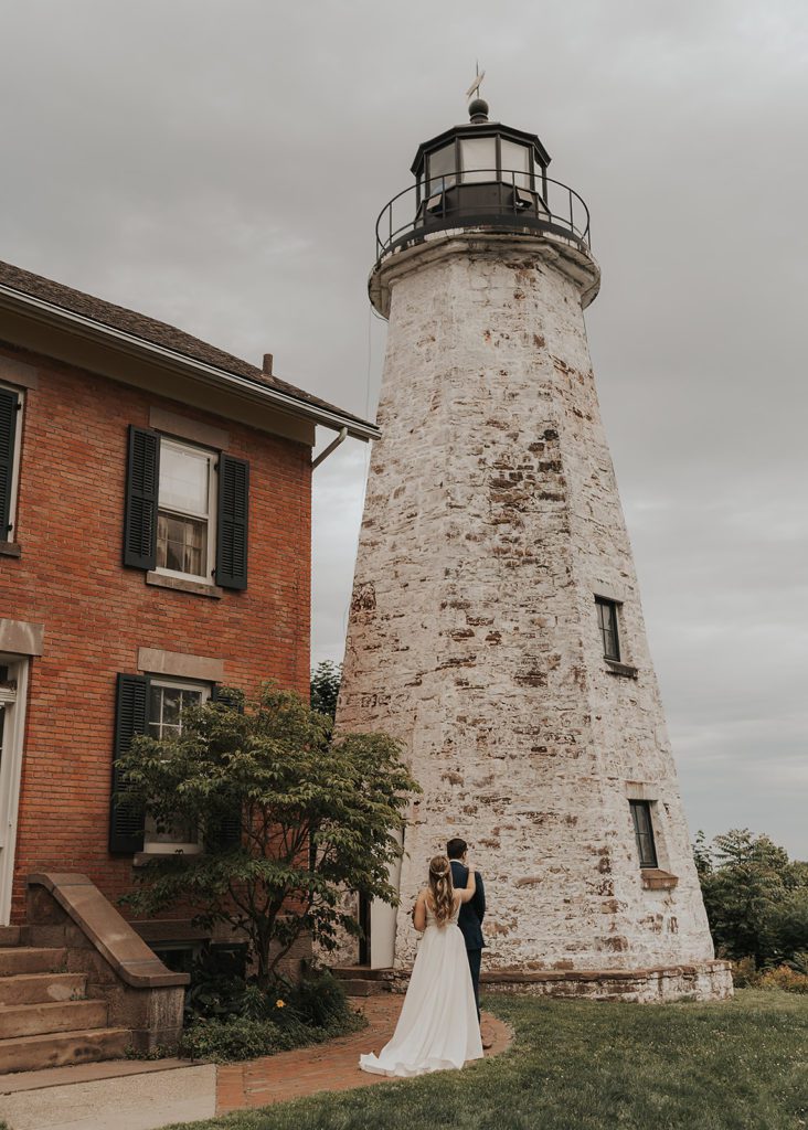 bride tapping groom on the shoulder for their first look at charolette lighthouse in rochester ny