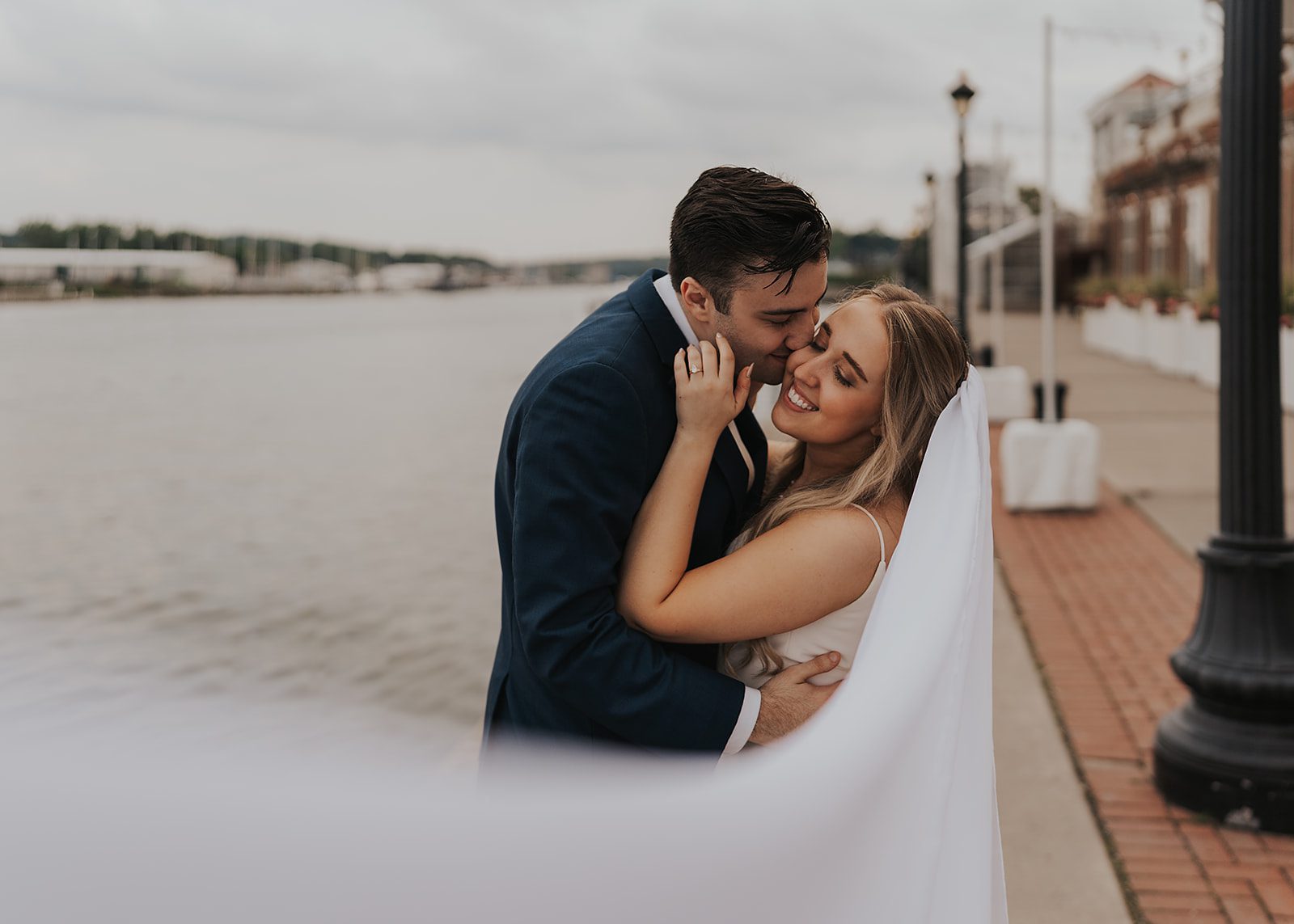 gorgeous veil photo of bride and groom kissing along the river in rochester ny