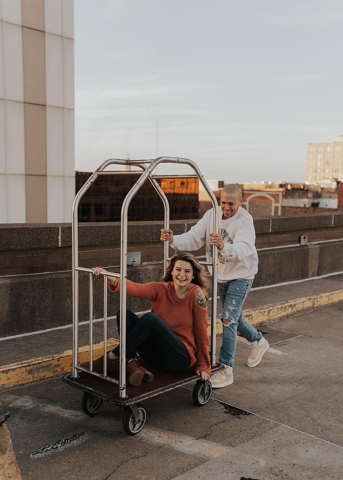fiance pushing girlfriend on a bell hop cart