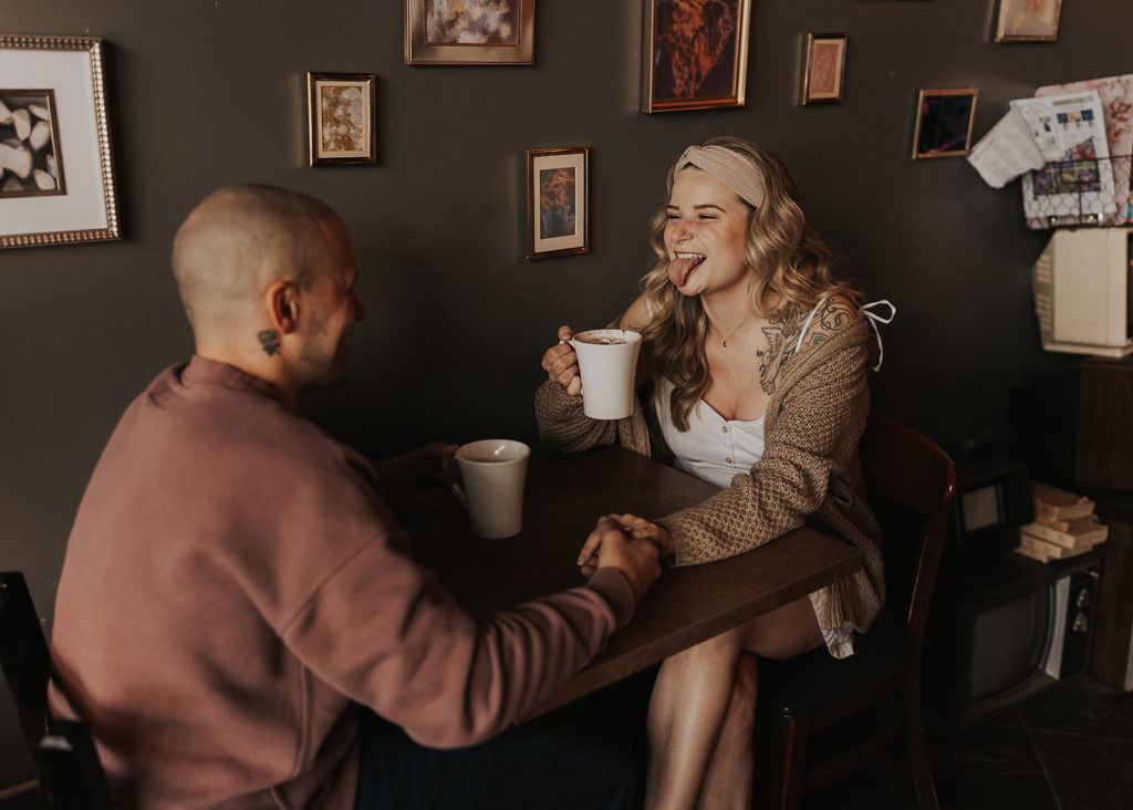 Couple sitting at coffee shop laughing during their engagement session