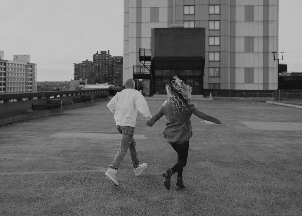 couple running away from the camera on top of a parking garage 