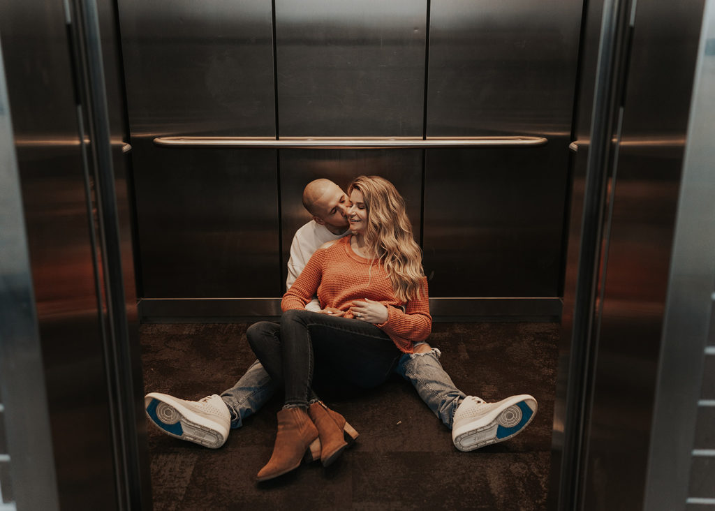 couple sitting in an elevator all snuggled up for their engagement session photos