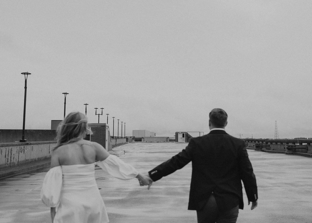 engaged couple holding hands and walking on the rooftop at a parking garage in Rochester NY
