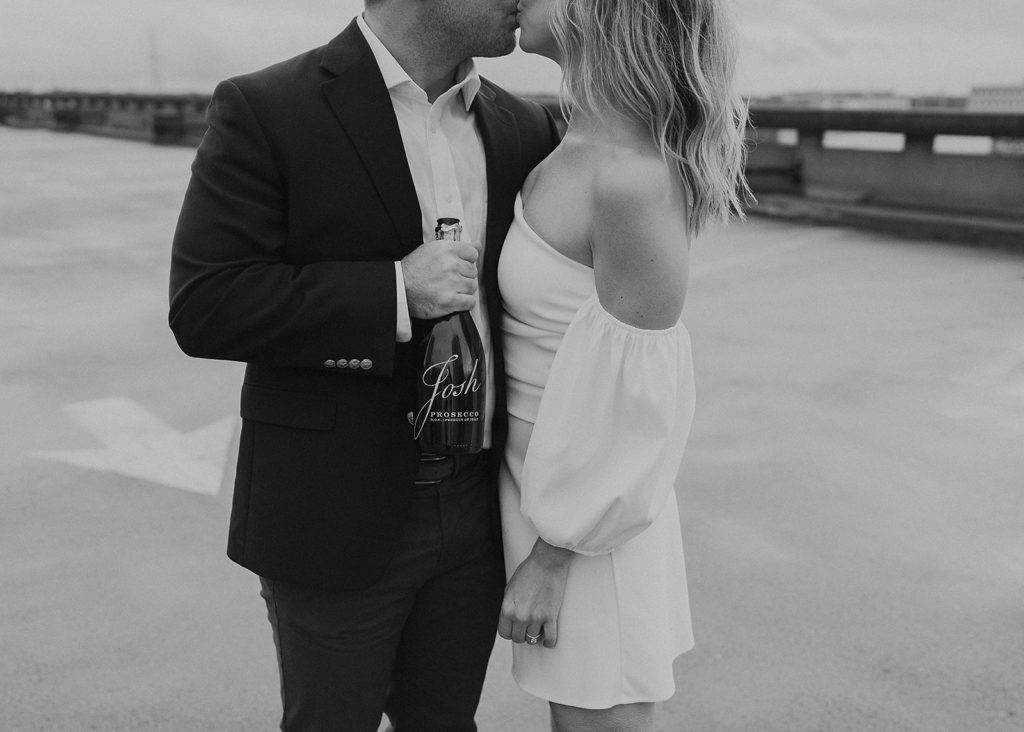 upclose black and white image of an engaged couple kissing on a rooftop in rochester ny after popping champagne during their engagement session
