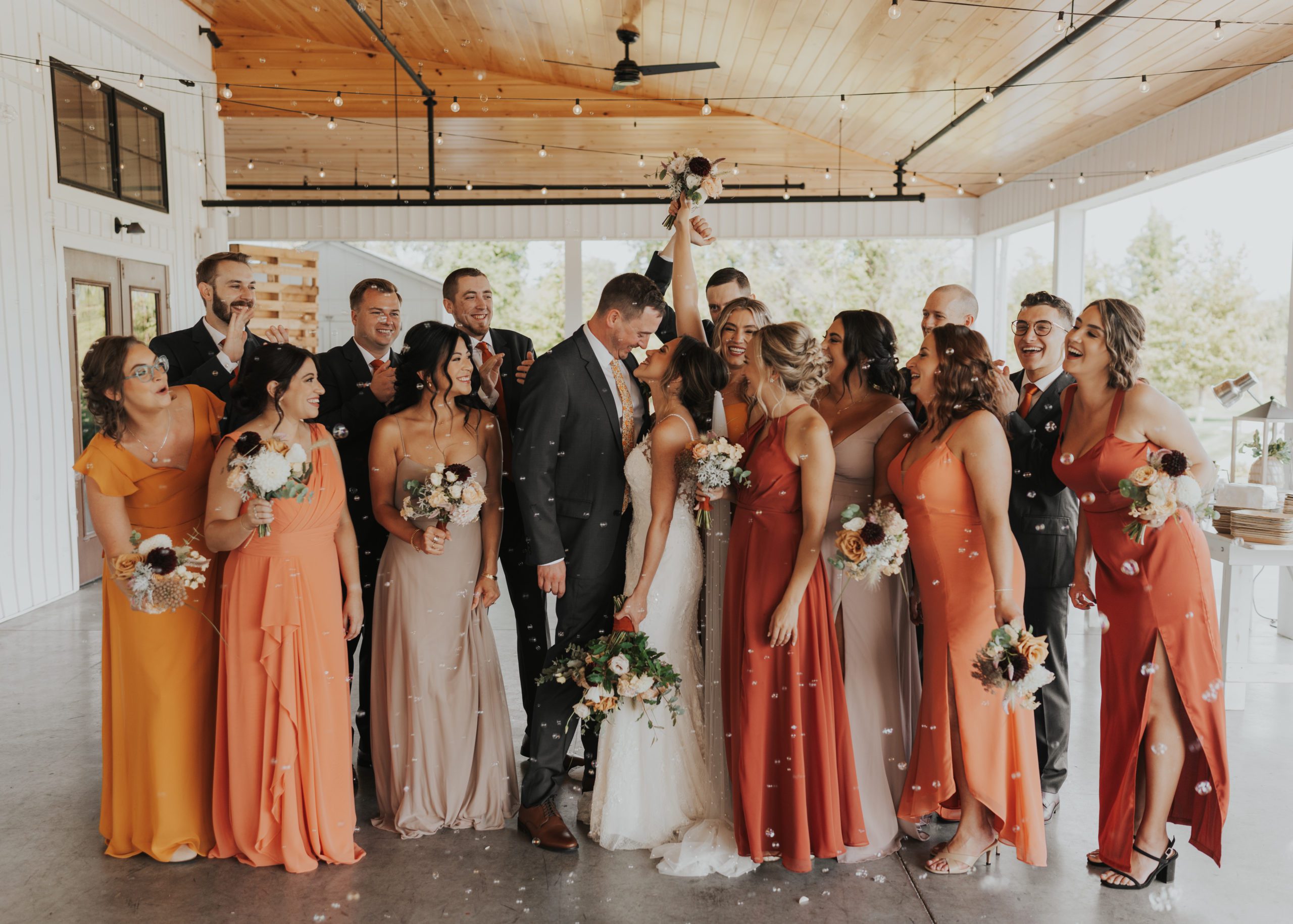 bride and groom kissing while their bridal party cheers around them