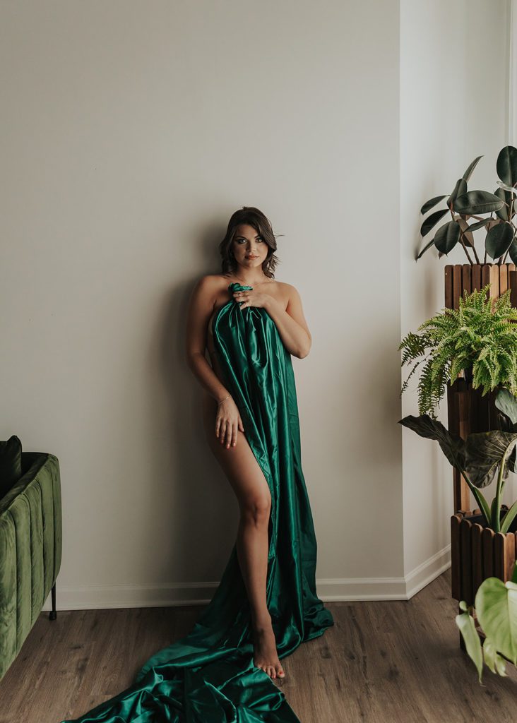 women leaning against the wall in the nude with a green blanket draped over her during a boudoir photoshoot at gallery 48 photo studio in Rochester NY