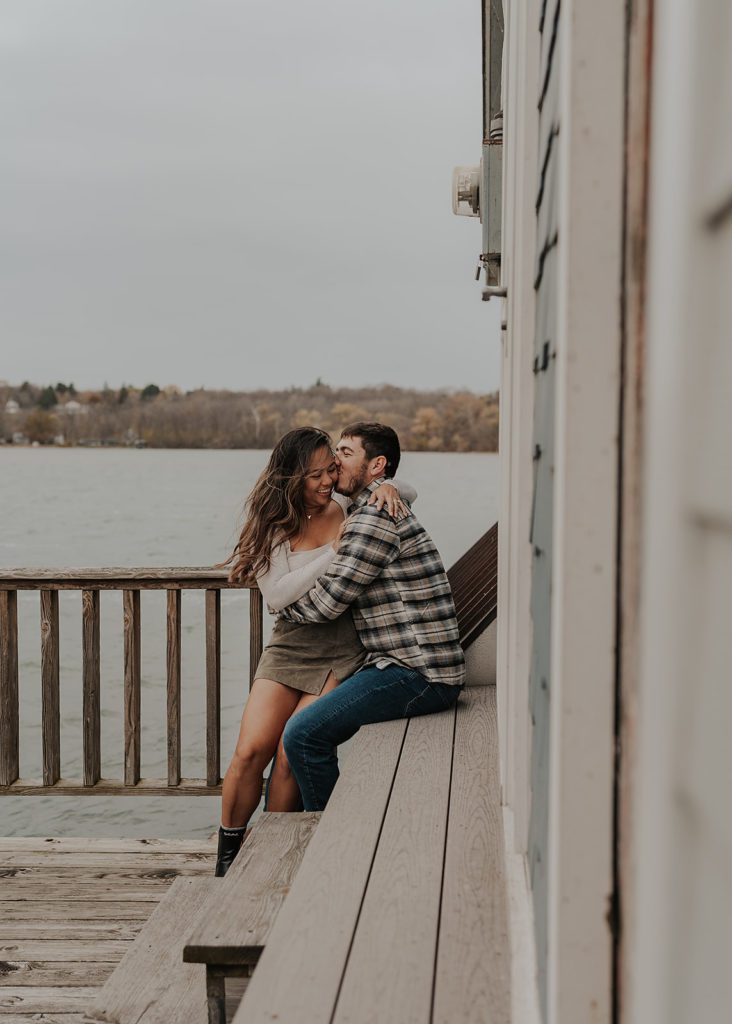 fiance kissing his girl friend on the cheek on a pier in Rochester NY