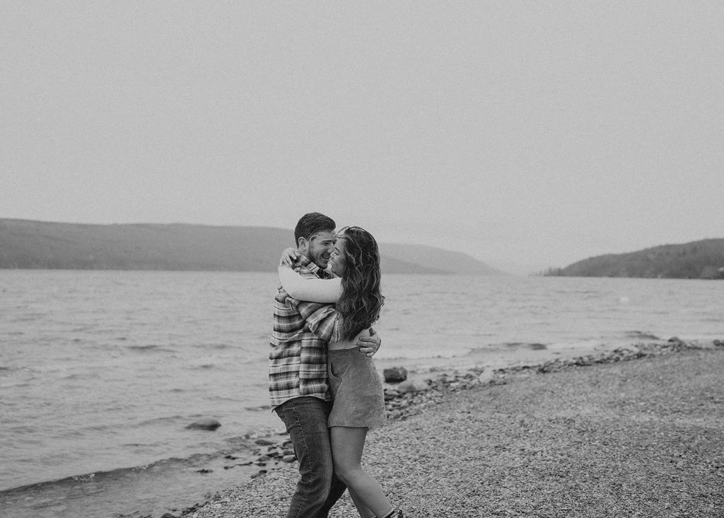 black and white image of engaged couple hugging on the beach in Rochester NY