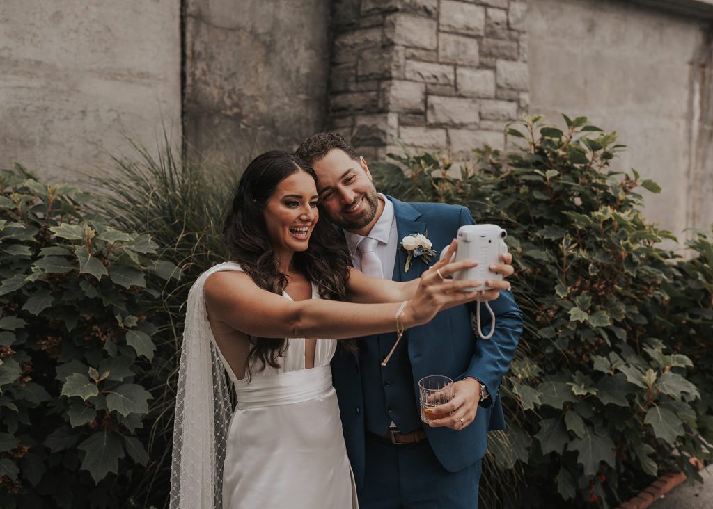 bride and groom taking a selfie with a polaroid in Rochester NY 