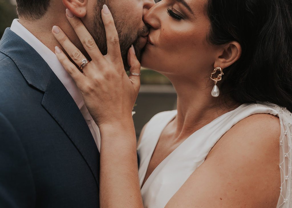 bride kissing the groom with her wedding ring being the center of the photo