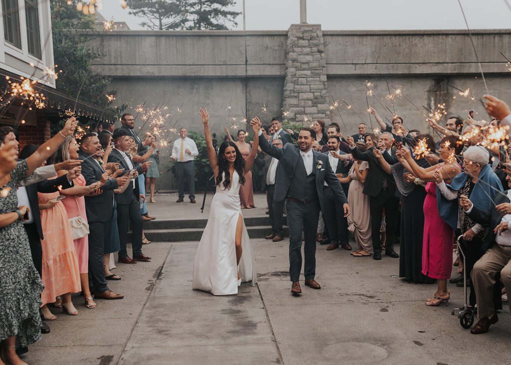 bride and groom doing their grand entrance into their first dance while their guests hold sparklers