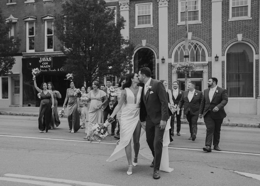 bride and groom walking down the street in rochester ny with their bridal party