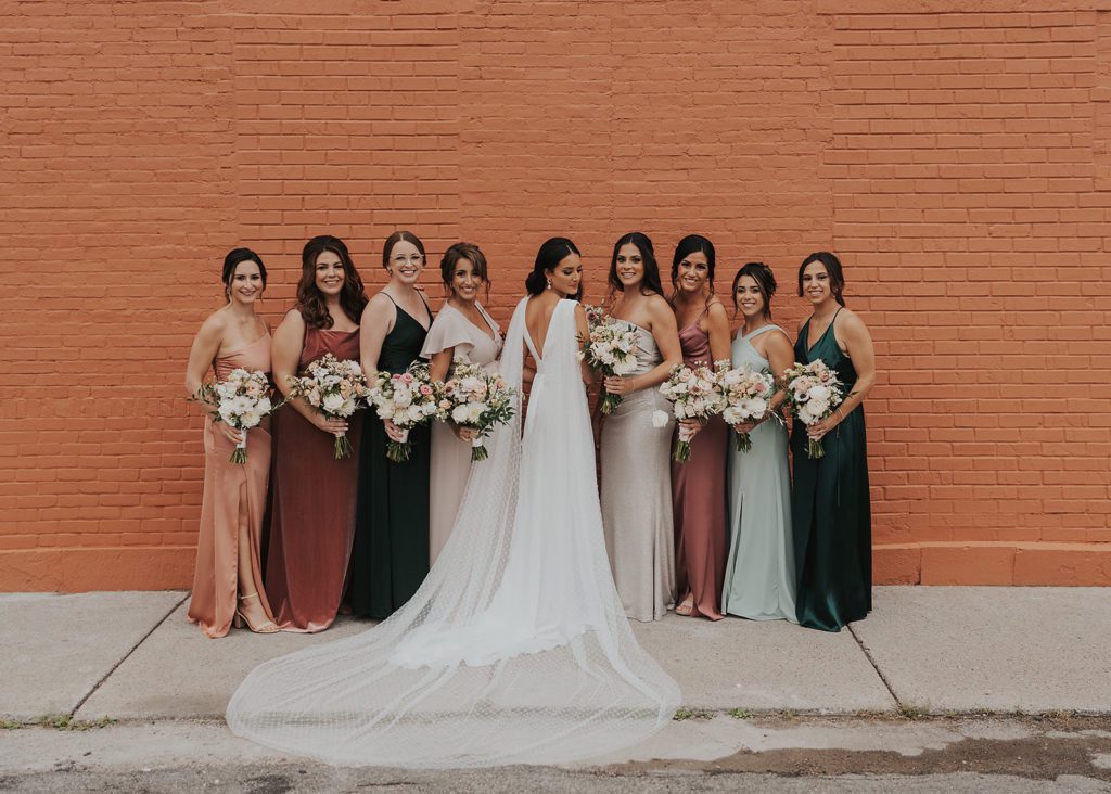 bride and bridesmaids smiling at the camera during their bridal party photos in Rochester NY