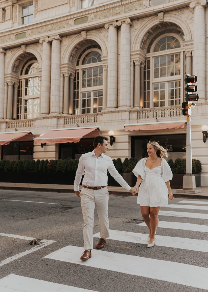 engaged couple holding hands and walking down the street in Nashville during their destination engagement photoshoot
