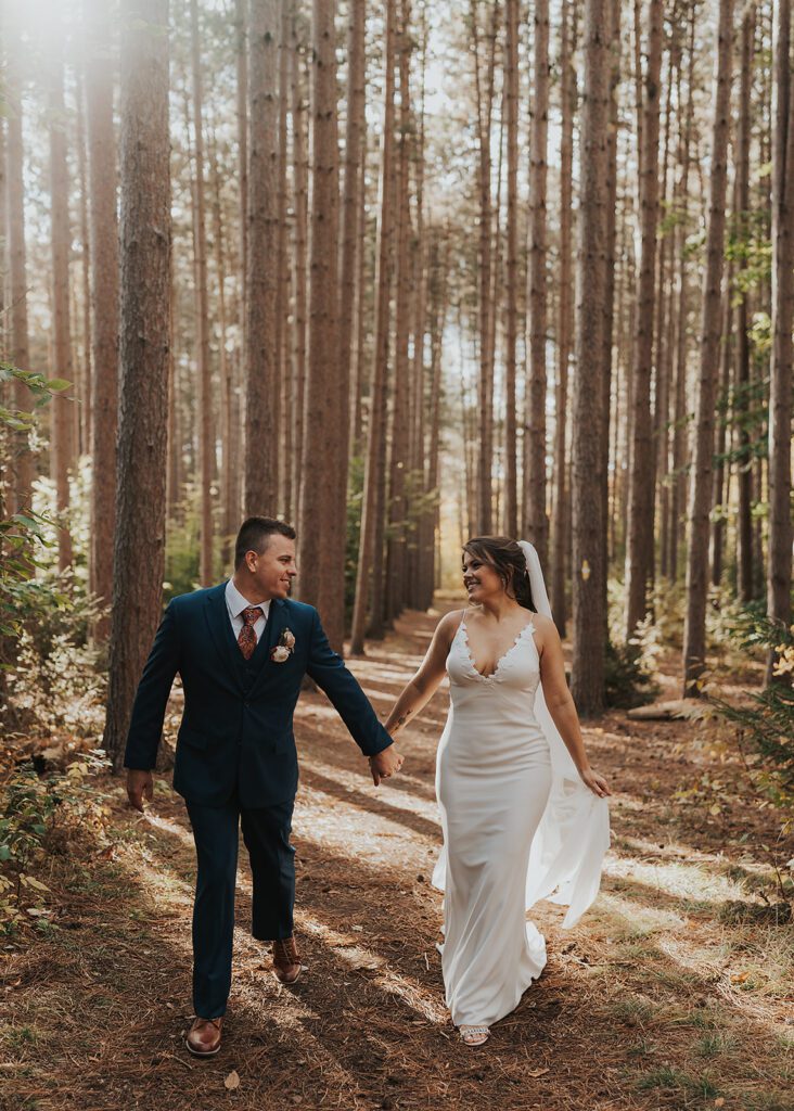 bride and groom walking through the forest at cummings nature center a rochester ny wedding venue