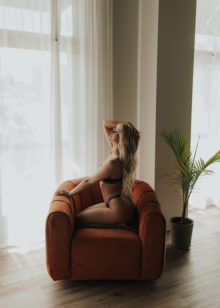women sitting on arm chair in lingerie during her boudoir photoshoot at gallery 48 photography studio in Rochester ny