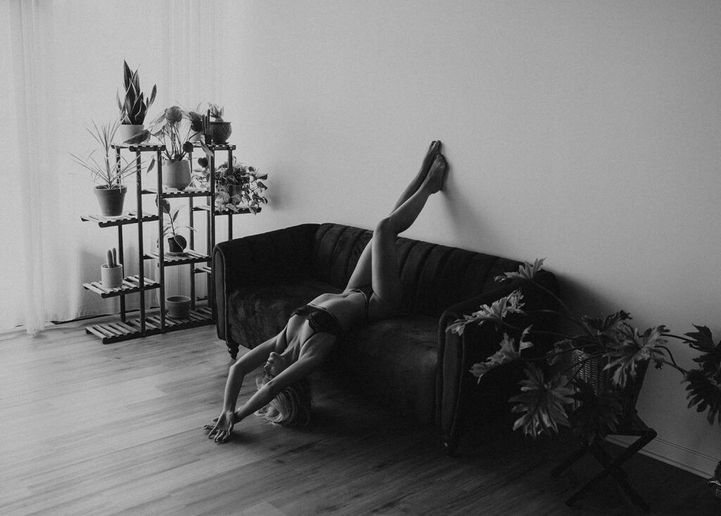 black and white image of women laying upside down on a couch in lingerie during her boudoir photoshoot at gallery 48 photography studio in rochester ny