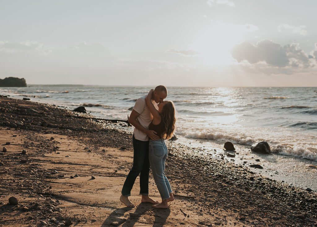 engaged couple standing on the beach hugging and looking at each other during golden hour during their beach engagement session