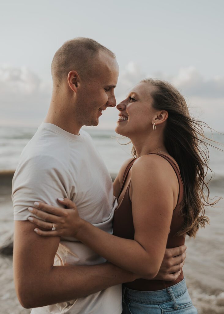 couples holding each other during sunset at the beach during their engagement session

