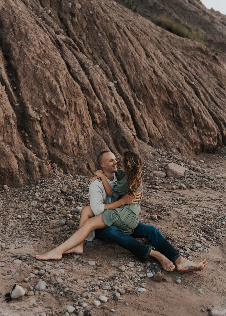 couple sitting together on the beach in rochester ny during their beach engagement photoshoot