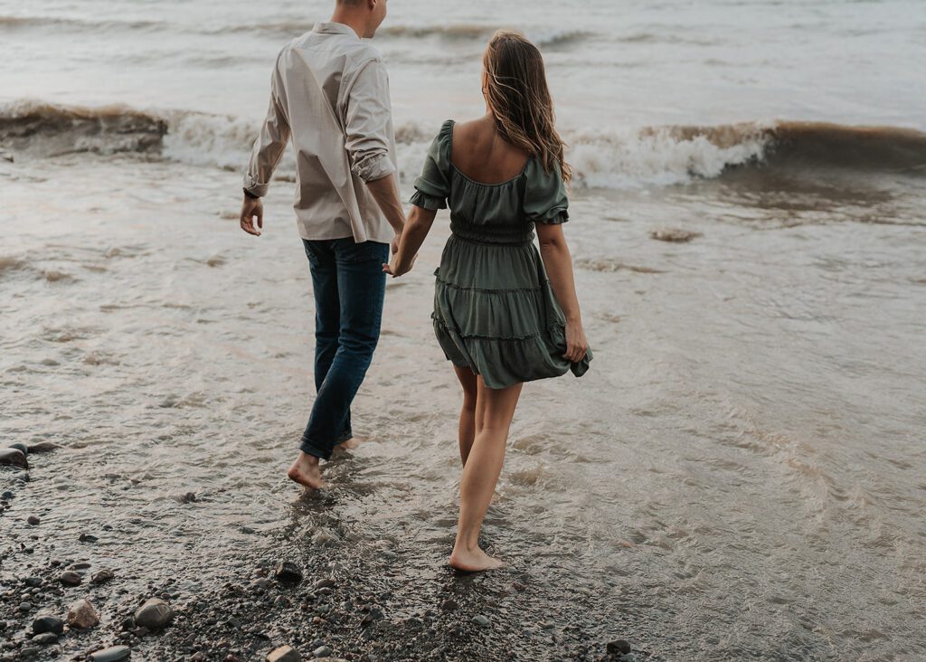 engaged couples walking into the water during their beach engagement photoshoot