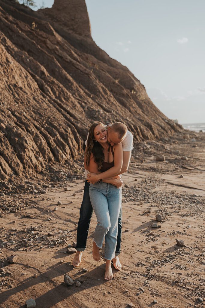 fiance hugging his girlfriend from behind during their beach engagement photoshoot