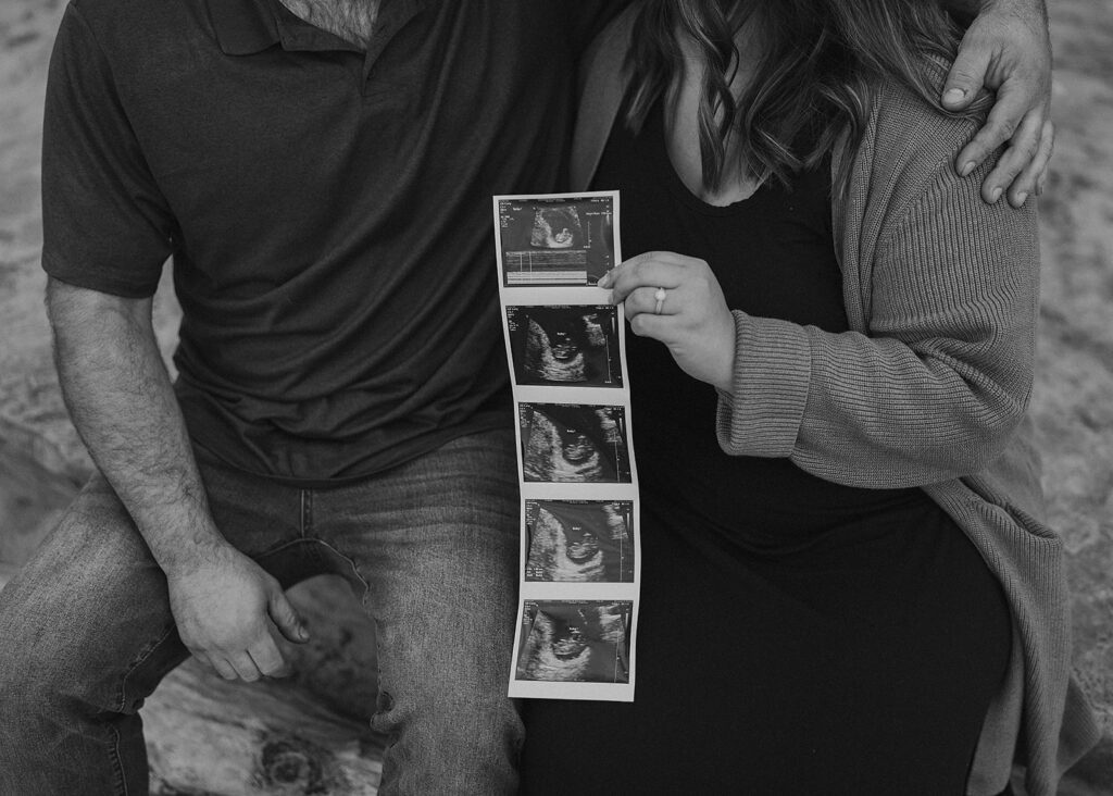 black and white image of family holding a sonogram photo during their rochester ny pregnancy announcement photoshoot