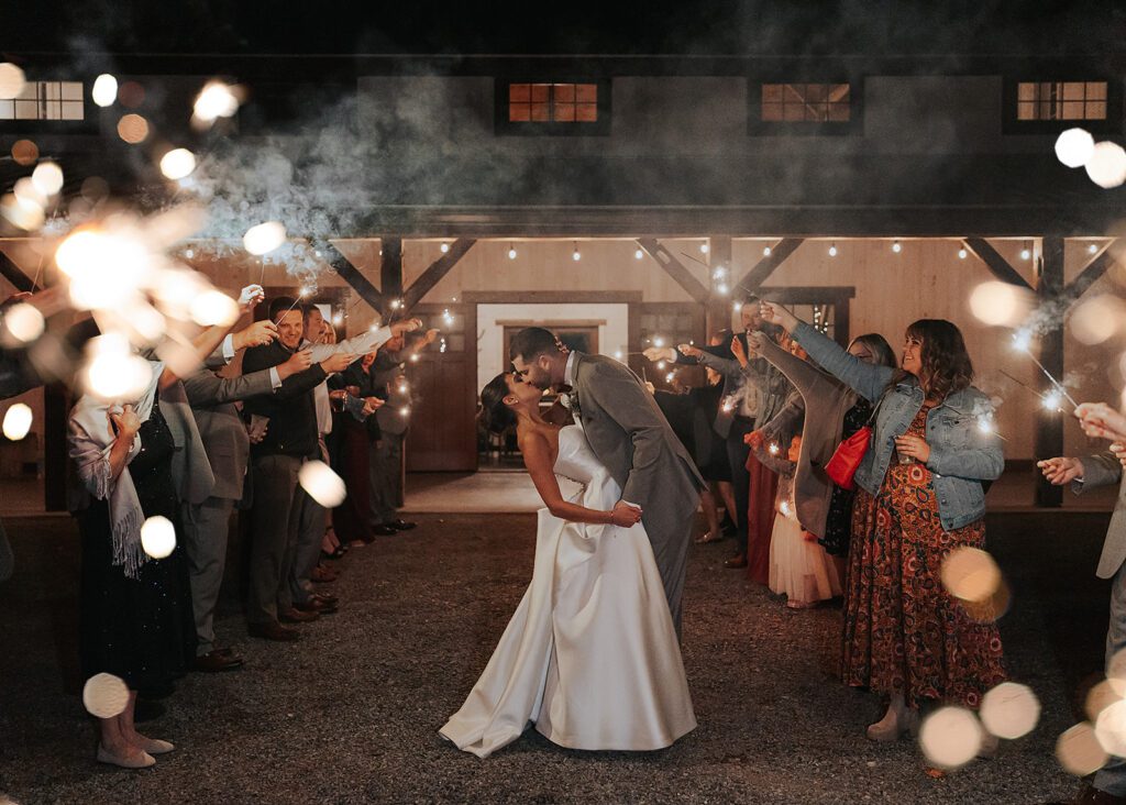 groom kissing and dipping the bride during their sparkler exit at wrens roost wedding venue in rochester ny